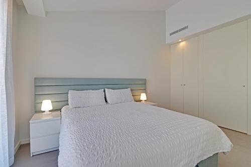 a white bedroom with a bed and two lamps at The Villa in Vilamoura