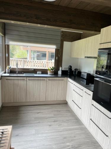 a kitchen with wooden cabinets and a large window at Chalet Alpaga 3 classé 4 étoiles in Châtel