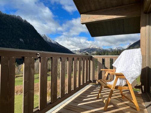 a rocking chair on a deck with a view of mountains at Chalet Alpaga 3 classé 4 étoiles in Châtel