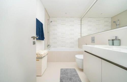 a white bathroom with a sink and a toilet at Exquisite 2BR in Sunrise bay at Emaar Beachfront in Dubai