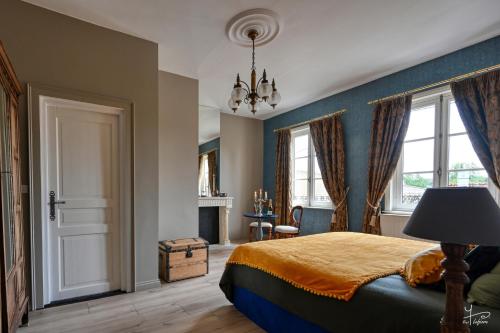 a bedroom with a bed and a chandelier at Manoir Marceau in Vieil-Hesdin