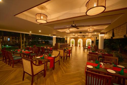 a restaurant with wooden tables and chairs and lights at Rhythm Kumarakom in Kumarakom