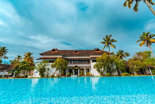 a swimming pool in front of a villa at Rhythm Kumarakom in Kumarakom