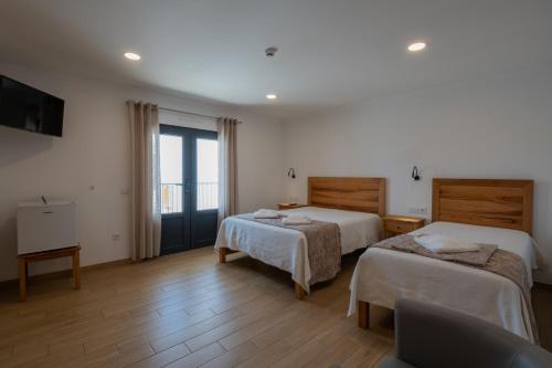 a hotel room with two beds and a television at Sol da Vila in Vila Nova de Milfontes