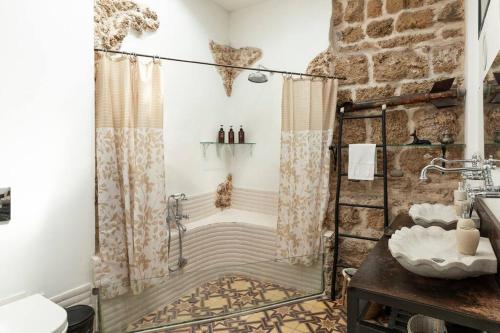 a bathroom with a shower and a stone wall at Luxury Villa by the Beach in Neve Tzedek's Heart! in Tel Aviv