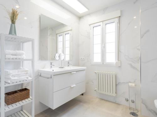 y baño blanco con lavabo y ducha. en housingcoruña ZAPATEIRA, en A Coruña