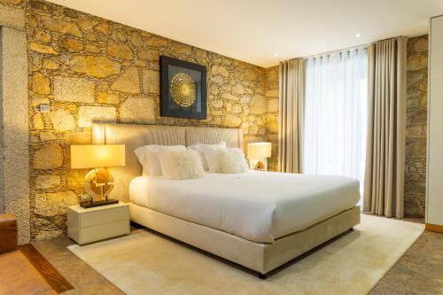 a bedroom with a large bed and a stone wall at Quercia Houses in Viana do Castelo in Viana do Castelo