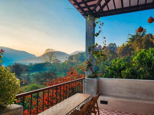a wooden bench on a balcony with a view of the mountains at Proud Phu Fah Maerim Resort in Mae Rim