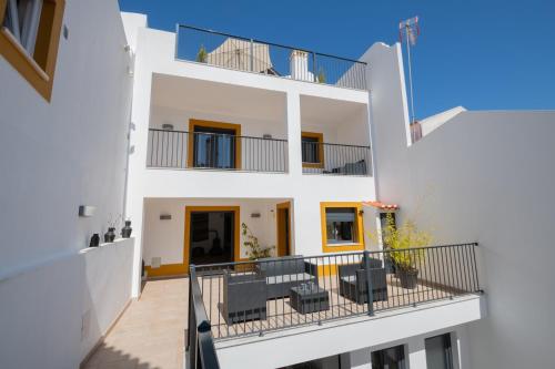 a white house with a balcony with chairs at Sol da Vila in Vila Nova de Milfontes
