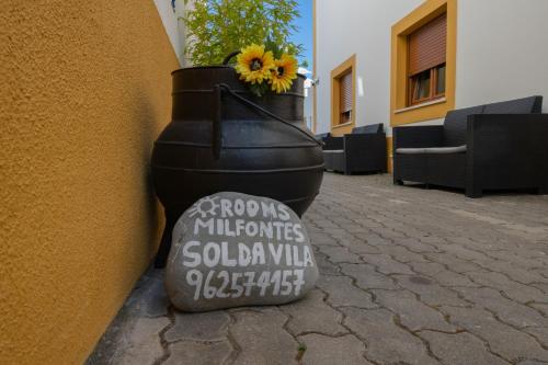 a pot with a sunflower in it next to a wall at Sol da Vila in Vila Nova de Milfontes