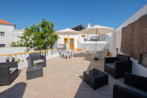 a patio with chairs and tables and umbrellas at Sol da Vila in Vila Nova de Milfontes