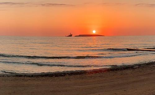 a sunset on the beach with a ship in the ocean at Kythera Beach Apartments in Diakofti