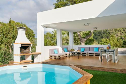 un patio al aire libre con piscina y chimenea en Villa Ses Abelles, en San José