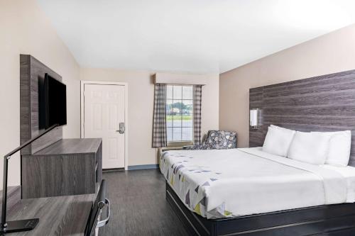 um quarto de hotel com uma cama e uma televisão em Baymont by Wyndham Commerce GA Near Tanger Outlets Mall em Commerce