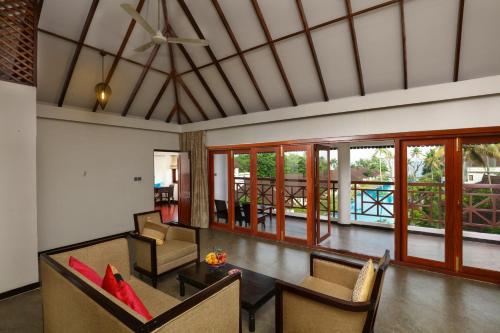a living room with a ceiling fan and chairs at Rhythm Kumarakom in Kumarakom