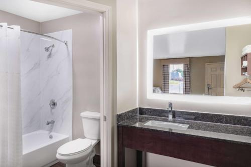 a bathroom with a toilet and a sink and a mirror at Baymont by Wyndham Commerce GA Near Tanger Outlets Mall in Commerce