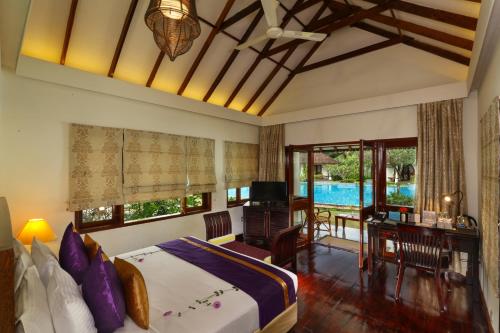 a bedroom with a bed and a desk and a television at Rhythm Kumarakom in Kumarakom
