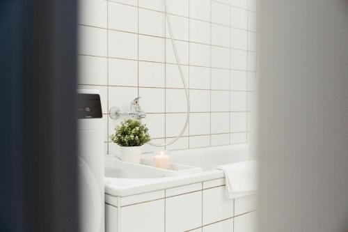 uma casa de banho em azulejos brancos com um lavatório e uma vela em Magdeburg Wohnkomfort - Vollausgestattet - Streaming - Familie & Business em Magdeburg