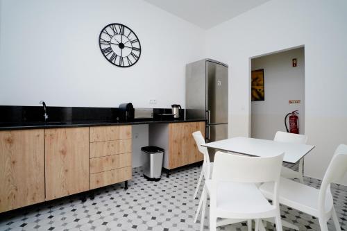 uma cozinha com cadeiras brancas, uma mesa e um relógio em Alameda Guesthouse by Boutique Taipas Garagem para motos em Portimão