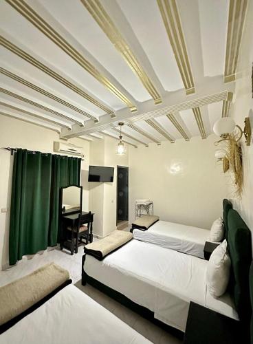 a bedroom with two beds and a piano in it at Hôtel Zaghro in Ouarzazate