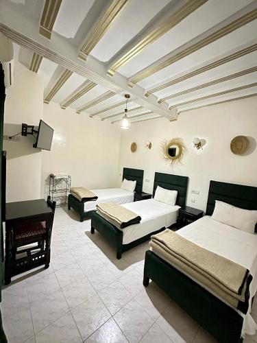 a bedroom with two beds and a piano at Hôtel Zaghro in Ouarzazate