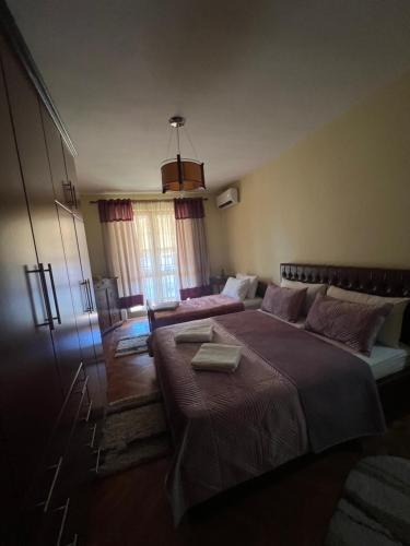 a bedroom with two beds and a large window at Apartament Qender in Elbasan