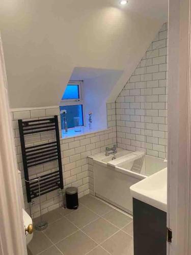 a white bathroom with a tub and a window at Isla’s Cottage in Stornoway