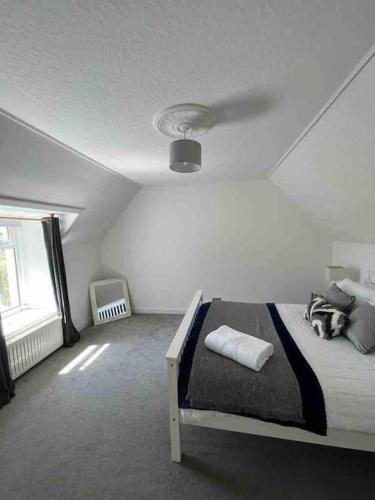 a white bedroom with a bed and a window at Isla’s Cottage in Stornoway