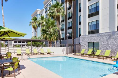a swimming pool with chairs and tables and a building at SpringHill Suites Phoenix Tempe Airport in Tempe