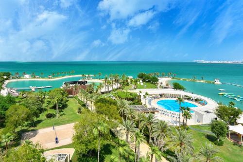 an aerial view of a resort with a pool and the ocean at Sheraton Grand Doha Resort & Convention Hotel in Doha