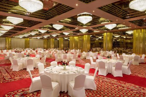 a large banquet hall with white tables and white chairs at Sheraton Grand Doha Resort & Convention Hotel in Doha