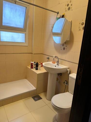 uma casa de banho com um WC, um lavatório e um espelho. em غرفة في منزل هادئ وأنيق em Sheikh Zayed