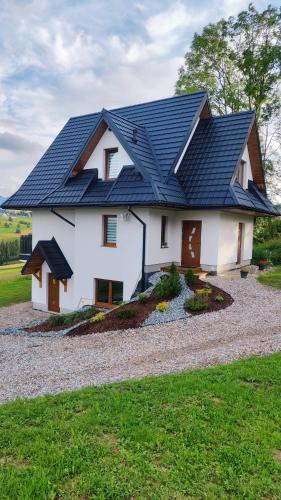 a white house with a black roof at Leszczyniański Domek in Biały Dunajec