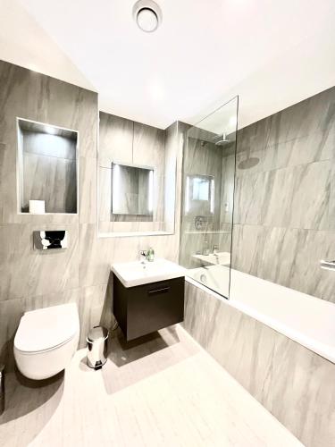 a bathroom with a toilet and a sink and a tub at Deluxe 2 Bed 2 Bath Flat - Windsor, Heathrow Airport, Slough Station in Slough