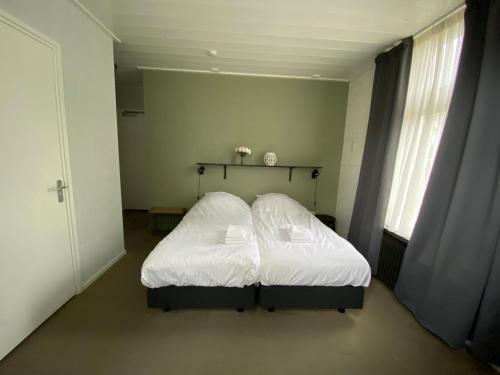 a bedroom with a white bed in a room at Het Wapen van Aelden in Aalden