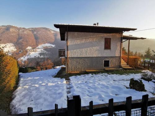 una casa con nieve en el suelo junto a una valla en La Casa di Raffaella - appartamento con giardino en Bracca