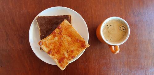 a plate with a piece of cake and a cup of coffee at Tiny Room Hostel in Nusa Penida