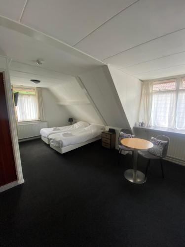 Habitación con 2 camas, mesa y sillas en Het Wapen van Aelden en Aalden