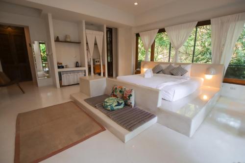a bedroom with a white bed and a large window at Proud Phu Fah Maerim Resort in Mae Rim