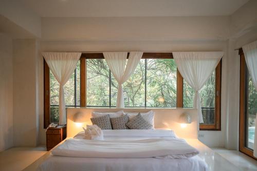 a bedroom with a large white bed with a window at Proud Phu Fah Maerim Resort in Mae Rim