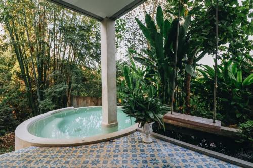 a jacuzzi tub in a garden with trees at Proud Phu Fah Maerim Resort in Mae Rim