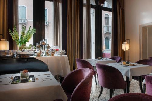 un restaurante con 2 mesas, sillas y ventanas en Ca' Gottardi, en Venecia