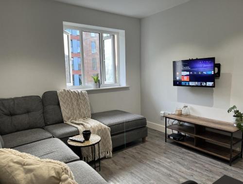 uma sala de estar com um sofá e uma televisão em Regency Apartment em Hemel Hempstead