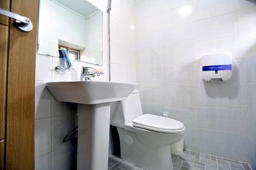 La salle de bains blanche est pourvue d'un lavabo et de toilettes. dans l'établissement Onsaemiro, à Seogwipo