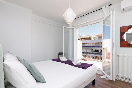 une chambre avec un lit blanc et une grande fenêtre dans l'établissement Wam YourHostHelper, à Cannes