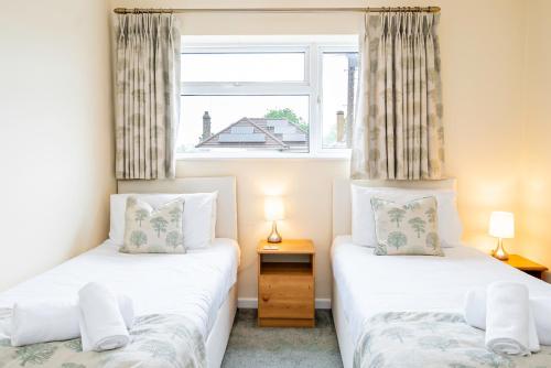 2 camas individuales en una habitación con ventana en Free Parking Good Location Lavender Harmony House, en Swindon