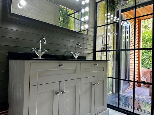 a bathroom with two sinks and a mirror at Peak District Romantic Retreat Outdoor Japanese Whirlpool bath in Stanton in Peak