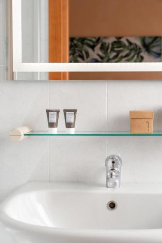 a bathroom sink with a glass shelf above it at Corallo Wellness Hotel in Diano Marina
