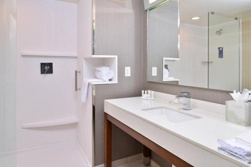 ein weißes Badezimmer mit einem Waschbecken und einem Spiegel in der Unterkunft Courtyard Kansas City Olathe in Olathe