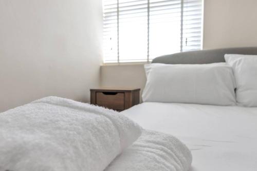 a bedroom with a bed with white sheets and a window at Coach House - Lovely 1 Bedroom Flat near Derby City Centre in Derby